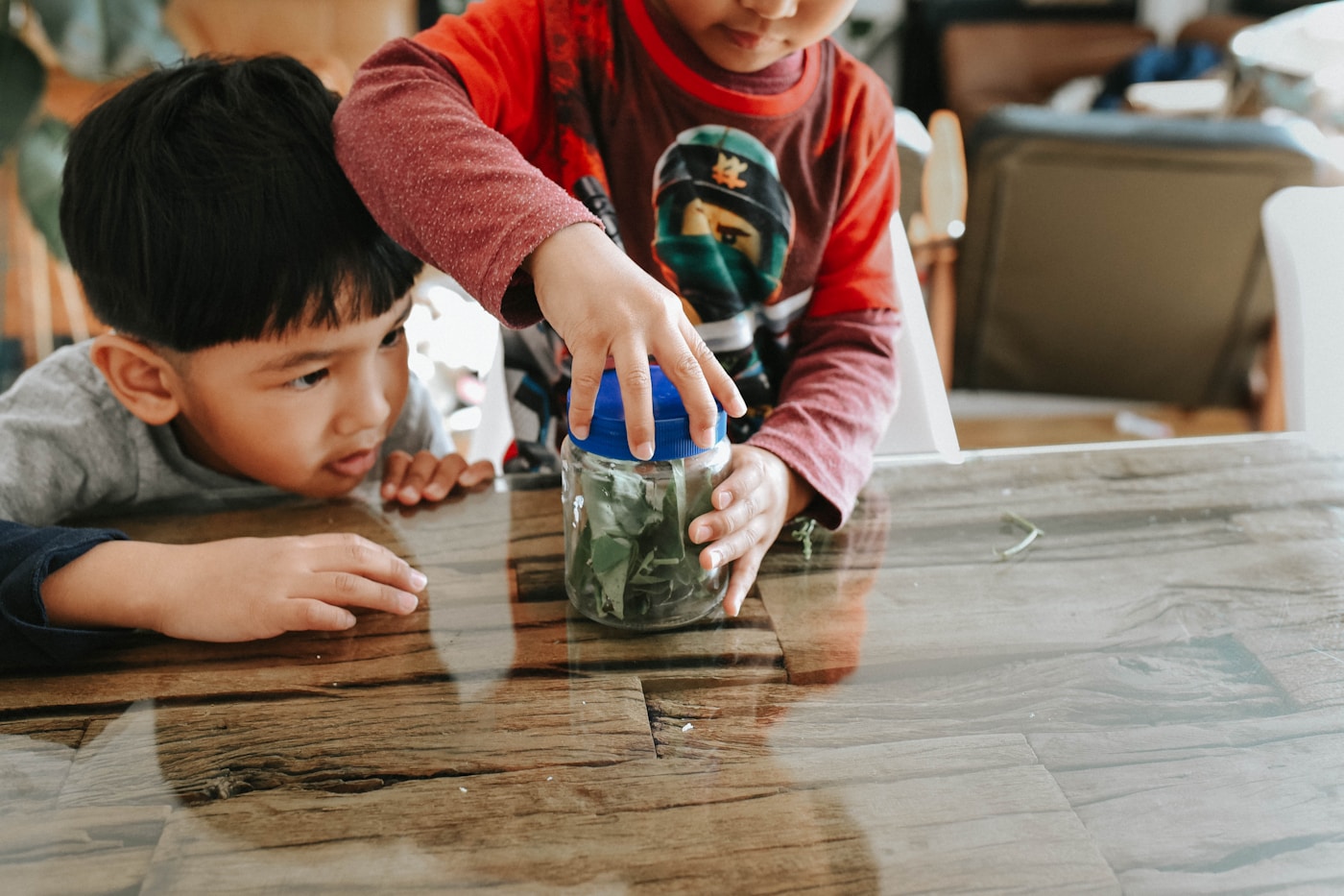 Two children saving coins together in a jar
