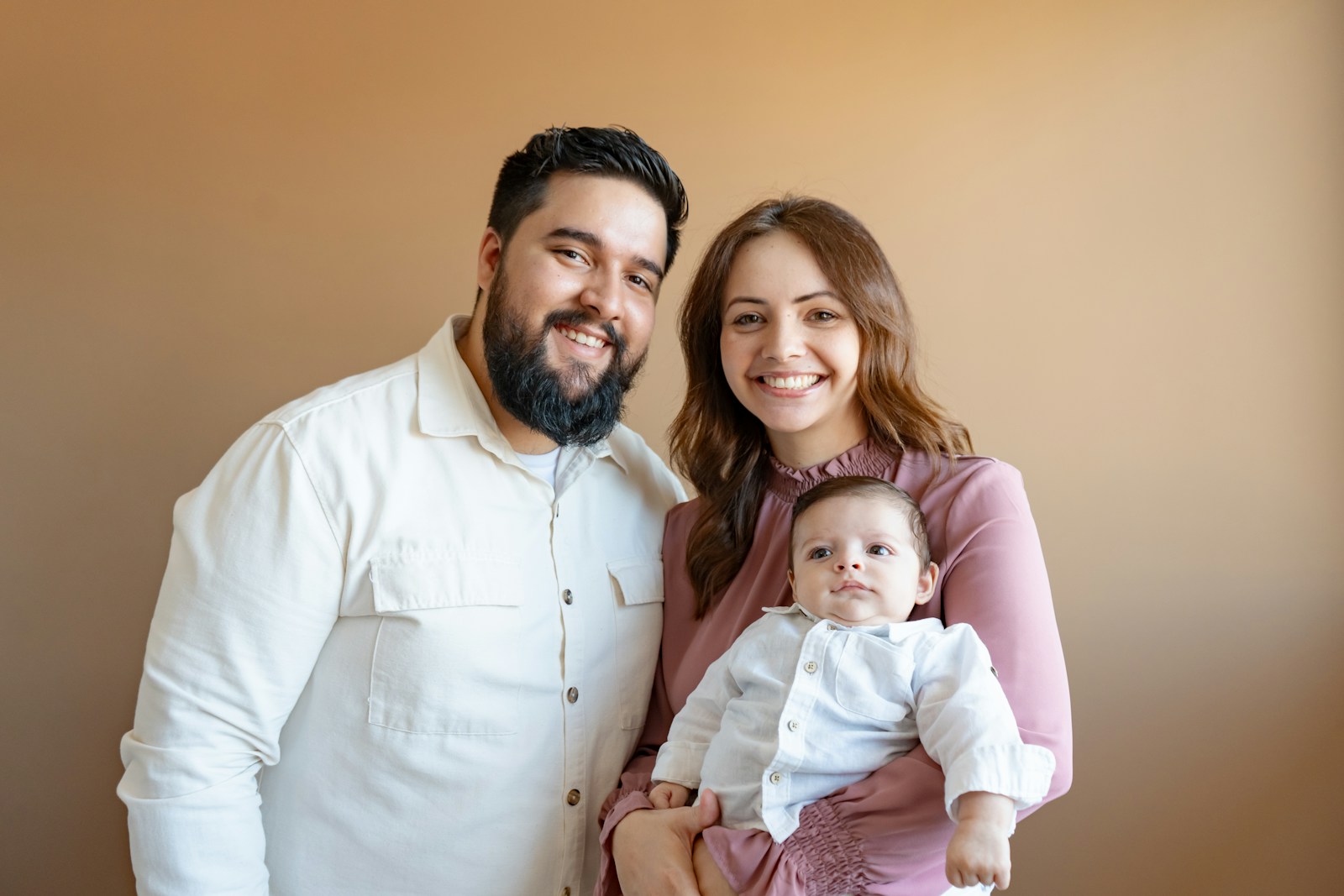 A smiling family of three with their baby